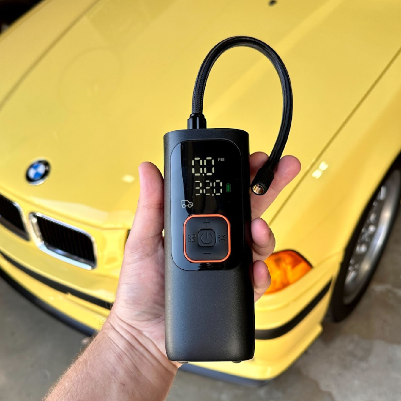 Image of the Bavsound Air Pump in front of a yellow BMW. 