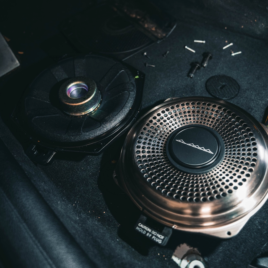 Photo of the quality material improvement of the Bavsound Ghost under seat subwoofer compared to the factory under seat subwoofer. 